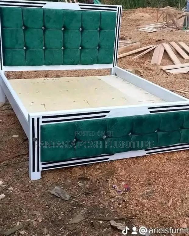 White Wooden Bed With Green Upholstered Button Tufted Panels.