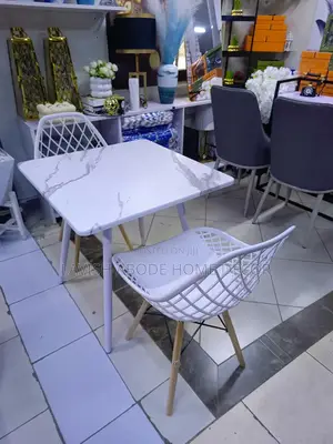 Modern Dinning Table With a Marble Effect Top With White Earmes Chairs