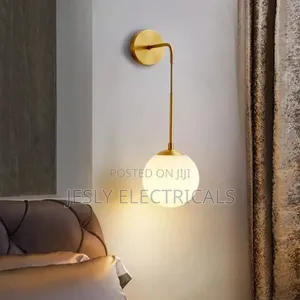 Modern Brass Wall Light With a White Glass Globe Shade.