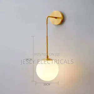 Modern Brass Wall Light With a White Glass Globe Shade.