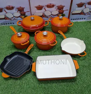 A Set of Enameled Orange Cast Iron Cookware With a Black Wok Pan