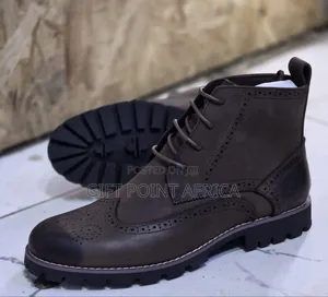 Brown Leather Wingtip Timberland Boots With A Lug Sole.