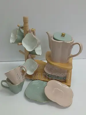 Ceramic Tea Set Featuring a Teapot, Cups, Saucers a Wooden Rack.