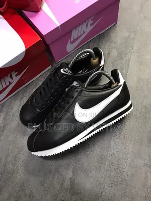 Black Nike Cortez Leather Sneakers With a White Swoosh Logo.