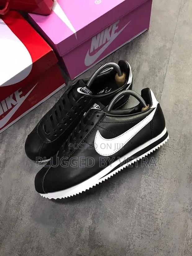Black Nike Cortez Leather Sneakers With a White Swoosh Logo.