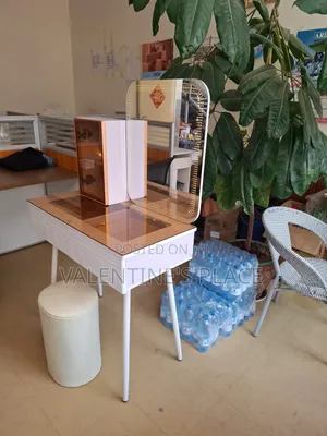 A Modern White Vanity Table With a Glass Top, Lighted Mirror