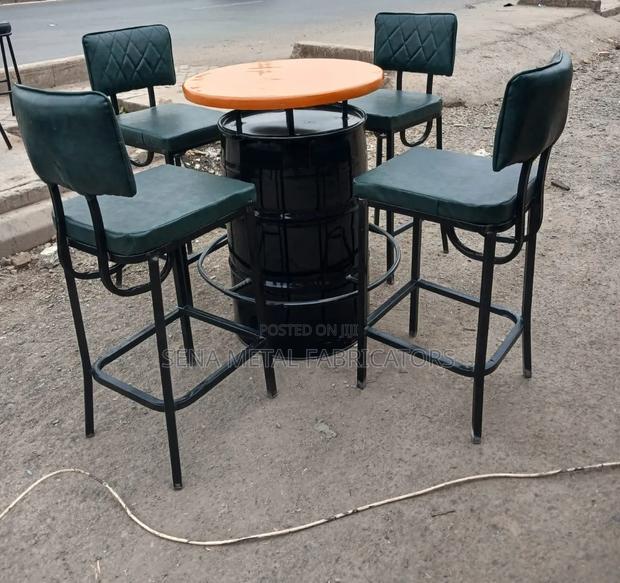 A Metal Drum Set With Green Bar Stools.