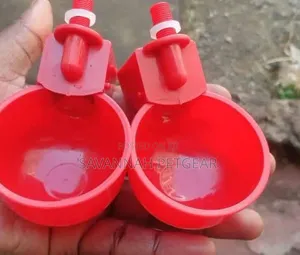 Red Plastic Automatic Poultry Drinking Cups Fitted Onto a Bucket
