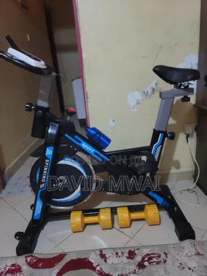 Fitness Bicycle Indoors With a Pair of Dumbells