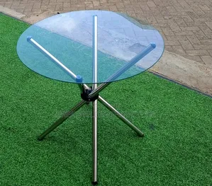 Round Glass-Top Table With a Distinctive Crossed Metal Leg Base