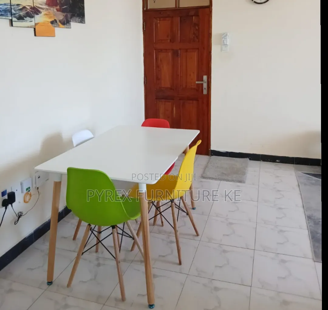 White Rectangular Table With 4 Colorful Eames Chairs